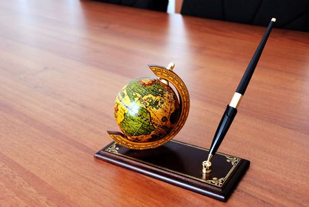 globe and pen on prop over brown office deskの写真素材