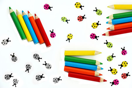various small crayons and ladybirds isolated over whiteの写真素材