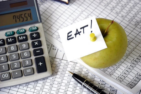 eat reminder on apple among papers and calculatorの写真素材