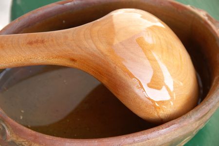 Yellow wooden spoon in brown earthenware closeupの写真素材