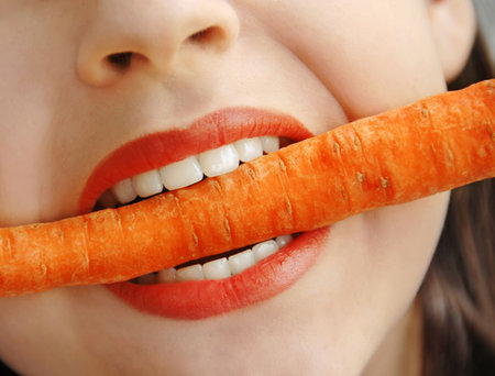 orange carrot in white girl teeth biteの写真素材