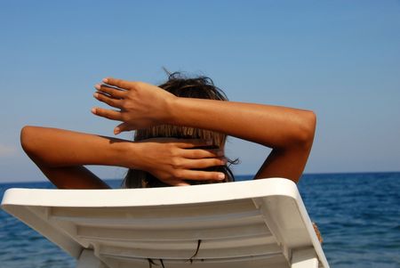 young girl lying on beach looking at sea viewの写真素材