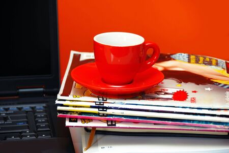 red cup on magazines and  black opened notebook on office desk, business still lifeの写真素材