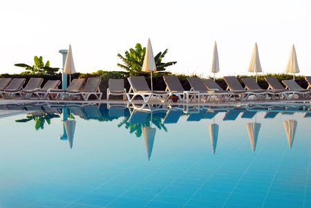 chairs row by blue swimming pool in resort in Turkeyの写真素材