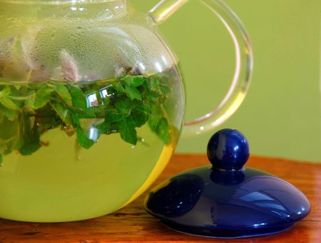 mint herbal tea in glass teapot over yellow backgroundの写真素材