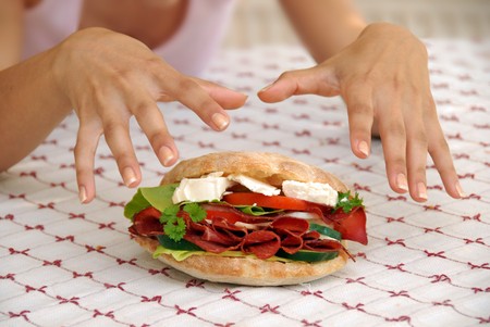 hungry girl hands over appetizing big sandwich with ham and cheeseの写真素材