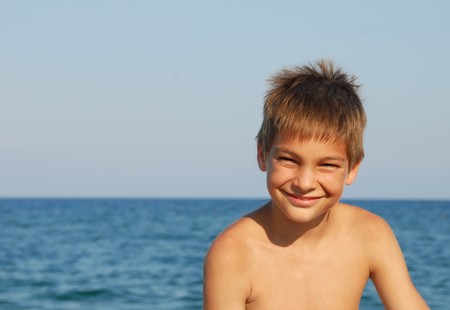 happy teen boy smiling portrait on seasideの写真素材