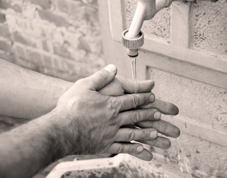 man washing hands outdoor in yard in black and white techniqueの写真素材