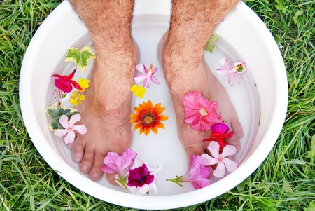 male hairy feet in bowl with water and flowersの写真素材