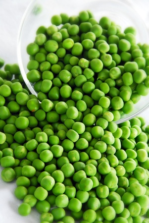 young fresh green spring peas scattered from glass bowlの写真素材