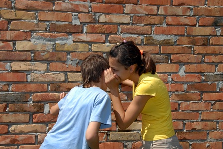 girl telling secret to boy closeup outdoorの写真素材