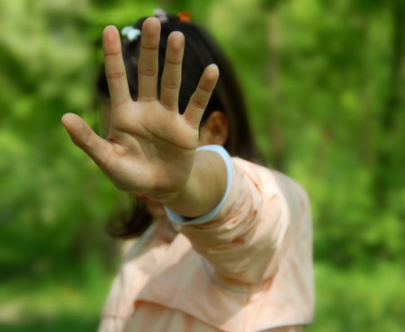 teen girl covers face by hand as rejection outdoorの写真素材
