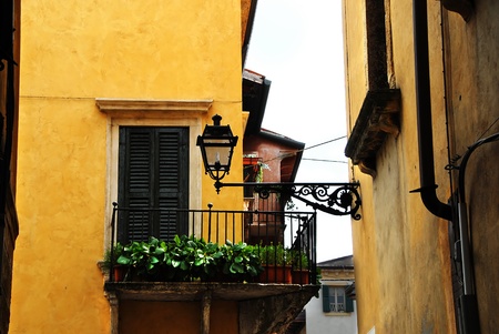 street lamp on building wall and balcony on yellow building facade, architecture details of Verona, Italyの写真素材