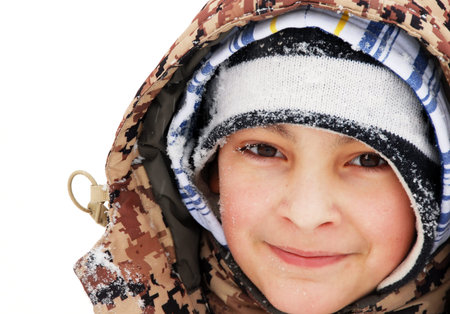 portrait of caucasian teenage boy in cap and hood at winter outdoor, snowflakes on eyelashes
