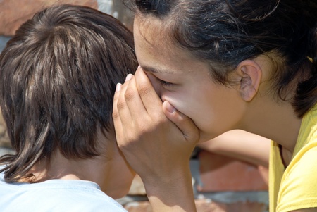 girl telling secret to boy closeup outdoorの写真素材