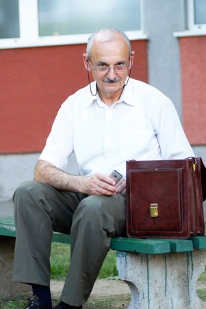 portrait of caucasian mature man in glasses with a mobile phoneの写真素材