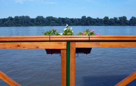blue river and horizon view from wooden terrace fence with a flower potの写真素材