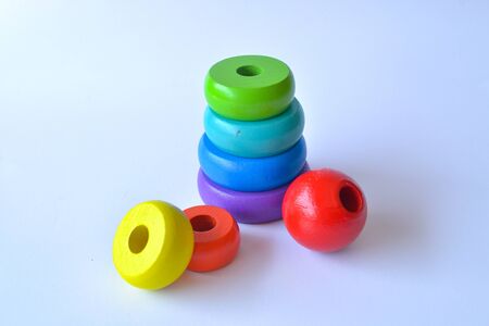 Pyramid build from colored wooden rings with a clown head on top. Toy for babies and toddlers to joyfully learn mechanical skills and colors. Isolated white background.の写真素材