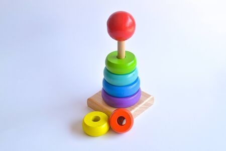 Pyramid build from colored wooden rings with a clown head on top. Toy for babies and toddlers to joyfully learn mechanical skills and colors. Isolated white background.の写真素材