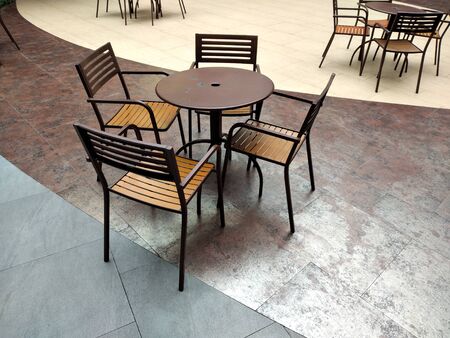 Set of chairs and dining tables for outdoor gardens. Made of tubular steel and finished in black with a patterned wicker chair covers.の写真素材
