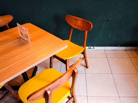 Minimalist dining table and chairs made of wood in a room with minimal lighting. Low light condition in indoor.の写真素材