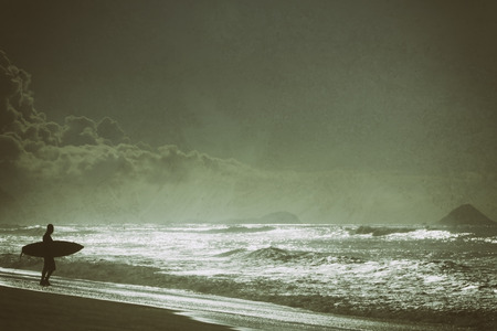 Man with a surfing board during sunrise on the beach in Rio de Janeiroの写真素材