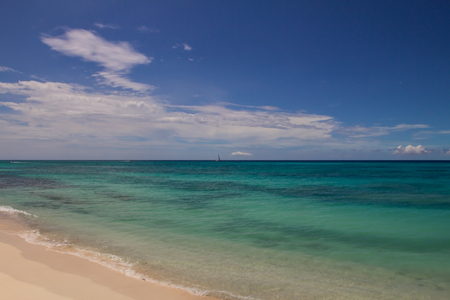Yacht on the horizon between a green ocean and the blue skyの写真素材