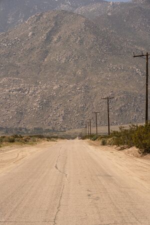 Lonely stretch of a dusty road somewhere in a desert near Palm Springs in Californiaの写真素材