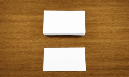 White, blank 3D rendering of mock up of stack of business cards with one extra sheet on brown wooden surface or table with copy space for text or images. Great for branding, promotions or advertising.の写真素材