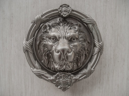 Metal lion head carving on marble slab.