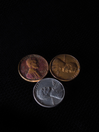 Three old American pennies side by side from the years 1943, 1940, 1936 sitting on top of wood carved flowers.の写真素材
