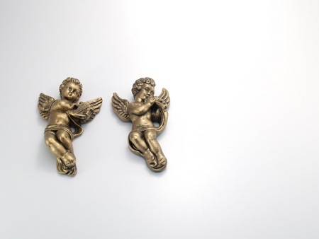 Two gold bronze cherubs beside each other laying down playing a harp and flute.の写真素材