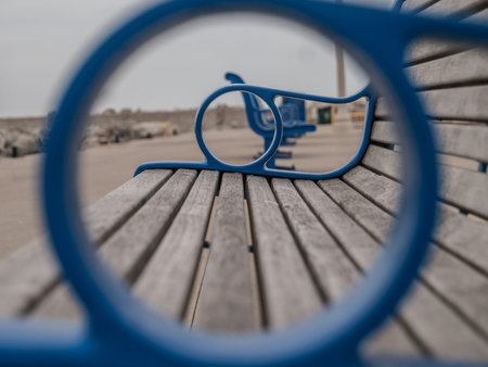 Line of wooden benches with blue arm rests on cement walkway in Bronte, Oakville, Ontario, Canada.