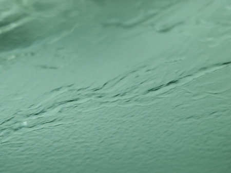 Wet green windshield at the car wash with streaks of water and blurry background.