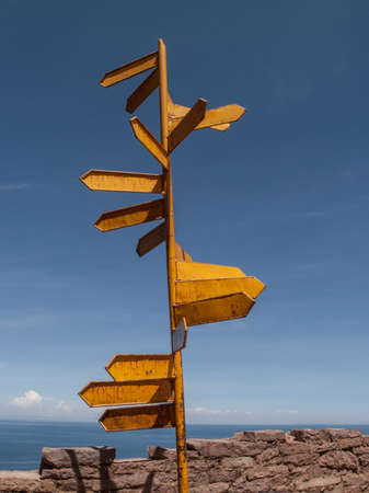 Yellow pole and directional signs with faded writing in Peru, South America.の写真素材