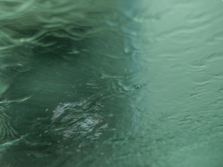 Wet green windshield at the car wash with streaks of water and blurry background.の写真素材
