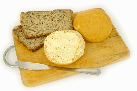 Composition with bread, rolls, butter and knife on boardの写真素材