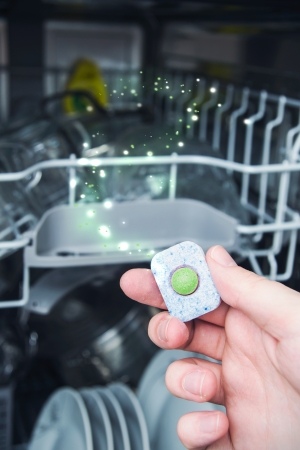 Hand holding dishwashing tablet. Dishwasher in backgroundの写真素材