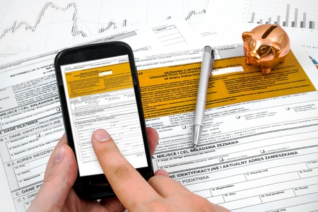 Man hand filling polish income tax form with mobile applicationの写真素材