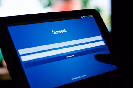 Woman pointing tablet with Facebook mobile app with polish interfaceのeditorial素材