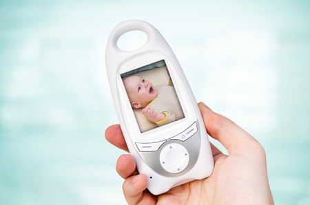 Hand holding video baby monitor for security of the baby の写真素材