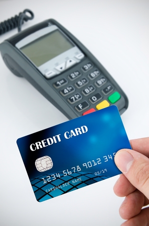 Hand holding credit card. Payment terminal in backgroundの写真素材