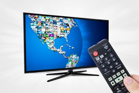 Widescreen high definition TV screen with sphere video gallery. Remote control in handの写真素材