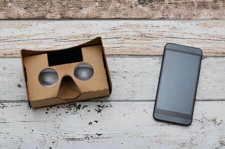 Virtual reality cardboard glasses. Easy way to watch movies in 3D. Shoot on wooden background.の写真素材