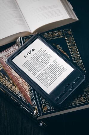 E-book reader device on desk in library. Alternative for traditional booksの写真素材
