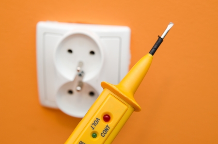 Electricity current meter, turn-screw near to the socket on orange wall.の写真素材