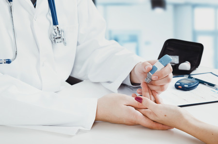 Doctor checking blood sugar level. doctor patient diabetes lancet glucometer blood glucose office conceptの写真素材