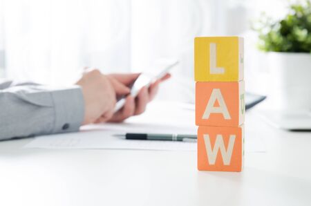 LAW word from toy blocks. Lawyer working in background. lawyer law justice judge scales courtroom blocks toy conceptの写真素材