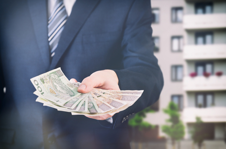 Home loan or investment in an apartment. Real estate agent holds Polish moneyの写真素材