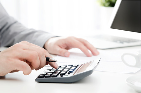 Accountant calculates tax. Working in the office with calculator. business finance tax work calculate conceptの写真素材